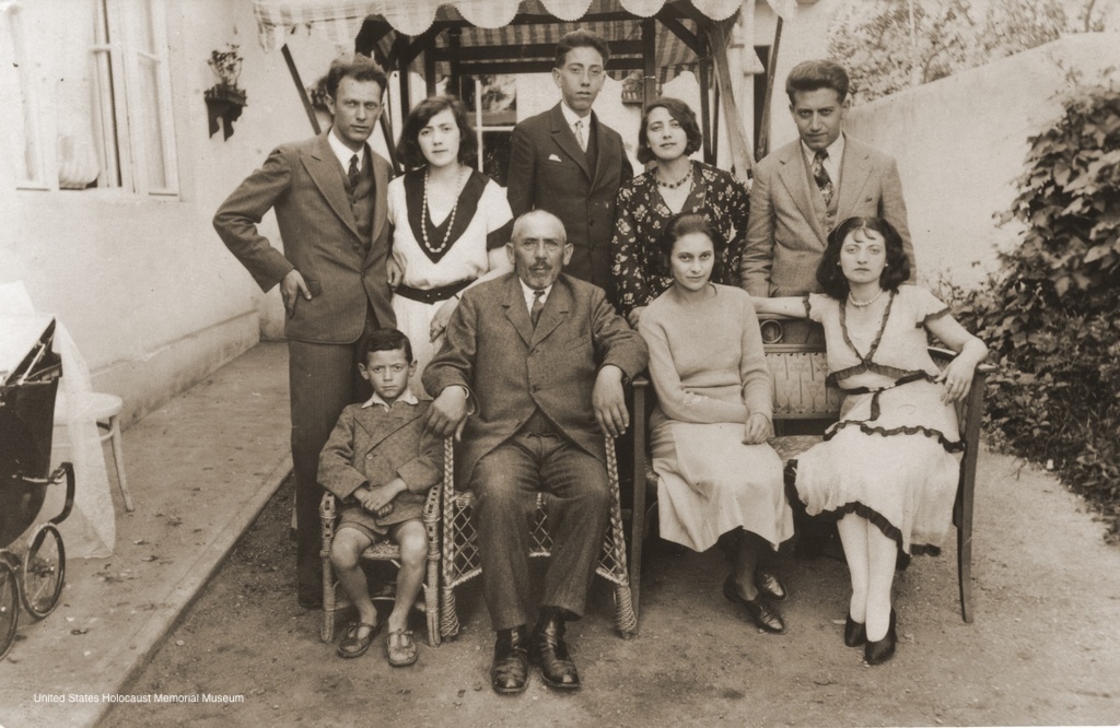 Photograph of the Vermes and Beck families taken outside Aladar Vermes' photo studio in Topolcany, Slovakia in 1931. Pictured in the front row from left to right are: Robert Vermes, Adolf Beck, Manci Vermes and an unidentified cousin. In the back row are: Aladar Vermes, Helena (Beck) Vermes, Pista Beck, Manci Beck and Ernest Beck. Erika Vermes is in the baby carriage at the left. Only Erika, Helena and Ernest survived the war.