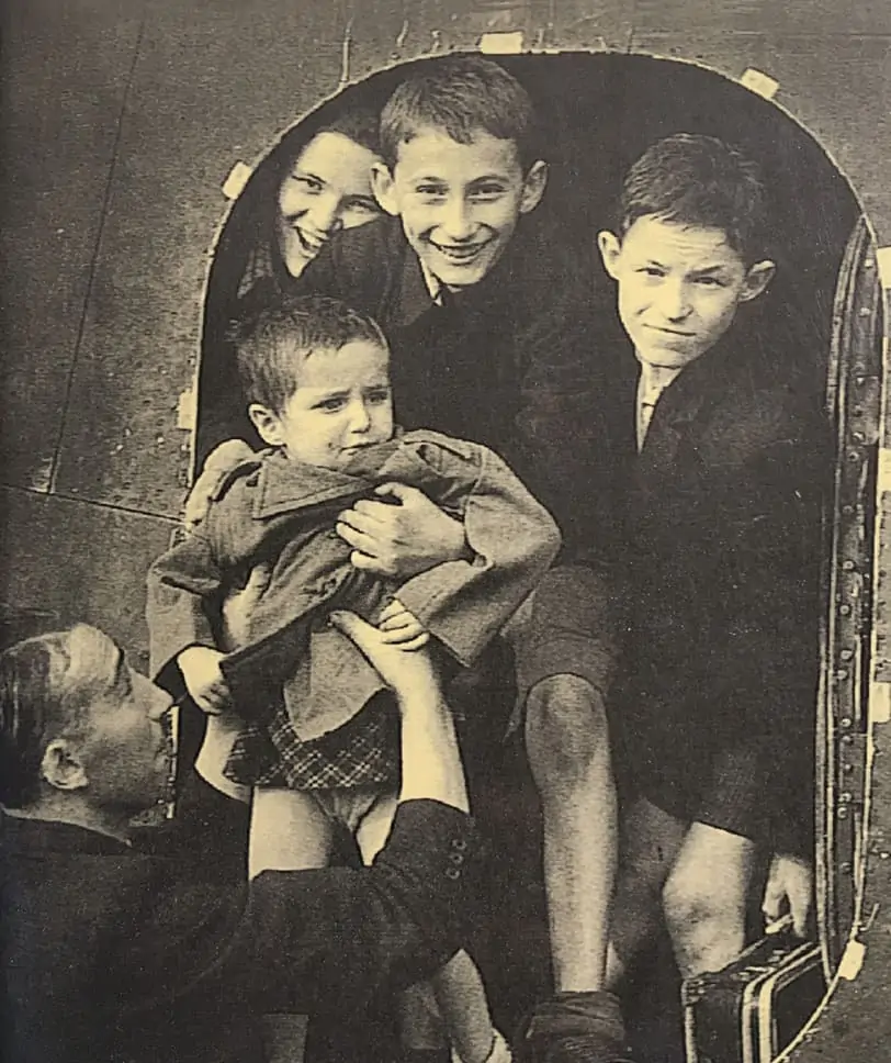 Photograph of Sidney Finkel passing Gad Josef to his older brother as they arrive in Windermere in August 1945.